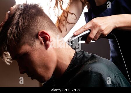 master hairdresser cuts guy making fashionable stylish haircut. Stock Photo