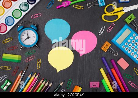 Thoughts and ideas at school concept. Top above overhead view photo of multicolored stationery around three idea bubbles isolated on blackboard Stock Photo