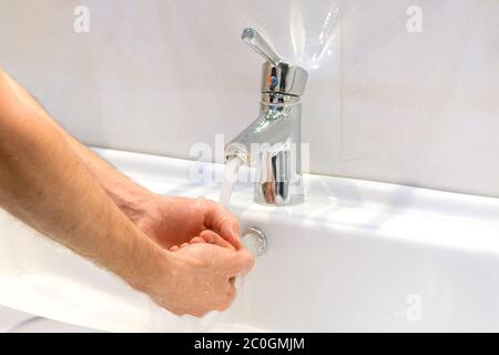 closeup of young caucasian man washing his hands with soap in the sink of bathroom Personal hygiene, protection against viruses and bacteria concept Stock Photo