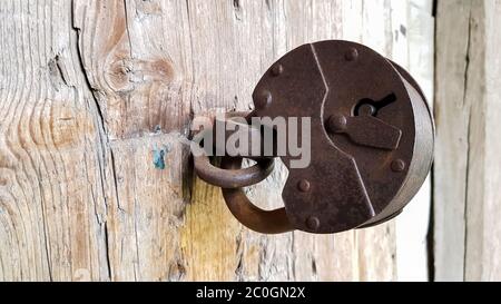 Old vintage metal padlock on a closed wooden door of an old farmhouse. The true style of the village. close-up. focus on the castle. Wooden background Stock Photo