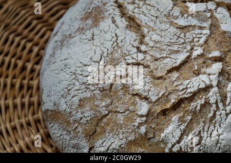 Fresh home baked artisan bread in wicker basket on wood table Stock Photo