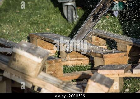 A wooden pallet being cut up with a chainsaw. Stock Photo