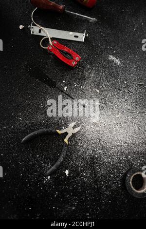 A set of tools for self-installation of the lamp lies on a black table, sprinkled with white dust. Husband for an hour. Household chores Stock Photo