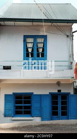 Direct front view of facade house at Da Lat, Vietnam, two storey house in light color wall, wooden window and door in blue paint Stock Photo