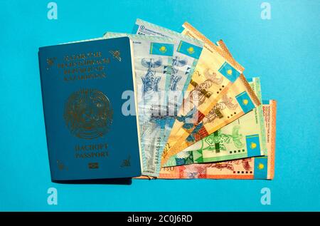 Dubai / UAE - June 10, 2020: Kazakhstan passport with national currency - tenge on blue background. KZ passport and kazakh money banknotes. Stock Photo