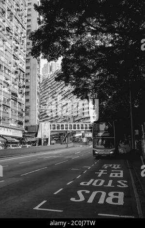 Double decker bus coming to a bus stop in residential part of Hong Kong Stock Photo