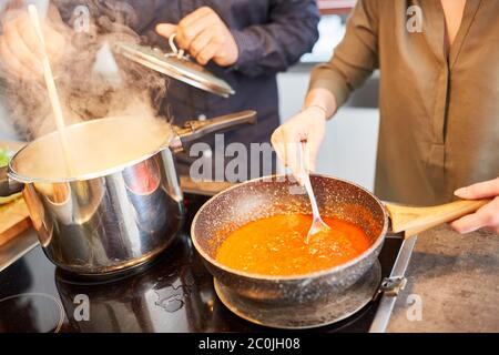 Couple cooks pasta with tomato sauce on the stove in the kitchen at home Stock Photo