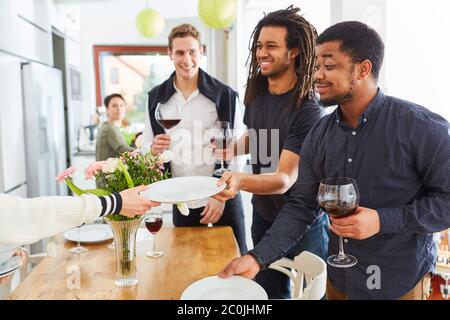Happy friends at table setting together in student shared flat for lunch Stock Photo