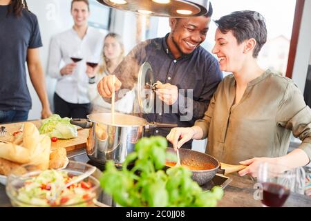 Friends cook pasta with tomato sauce in shared kitchen together for meal together Stock Photo