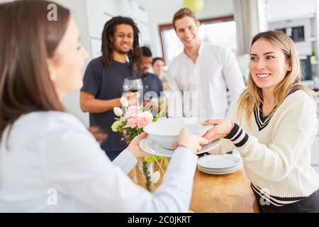 Friends together lay table with dishes for eating together in the kitchen of a shared apartment Stock Photo