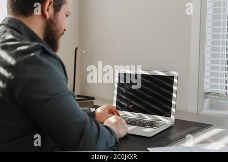 Male programmer writing program at office on laptop, typing on keyboard. Stock Photo