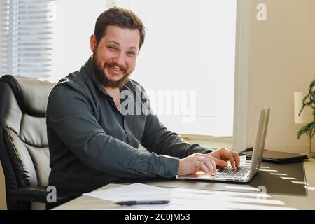 Web developer sitting at office desk working on laptop computer. Stock Photo