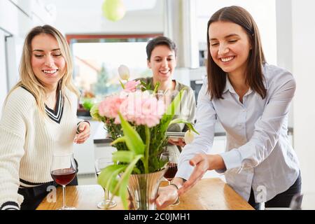 Woman decorating table with girlfriends and laying for lunch in shared kitchen Stock Photo