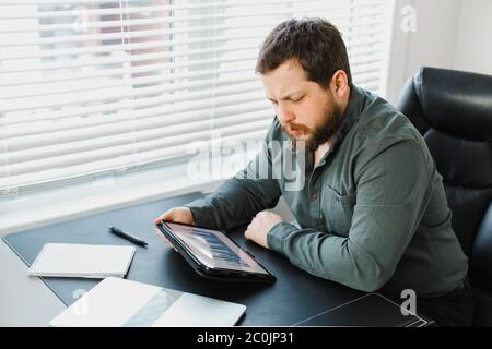 Serious male executive using digital tablet and working with documents. Stock Photo