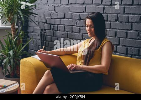 Positive delighted office worker making notes while reading Stock Photo