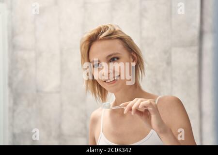 Cheerful lady holding a toothbrush in her hand Stock Photo