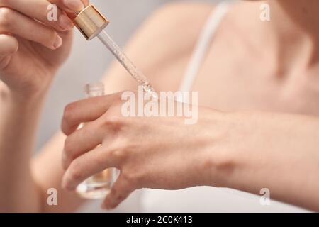 Female holding a pipette and a glass bottle Stock Photo