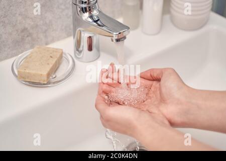 Cupped female palms under the bathroom faucet Stock Photo