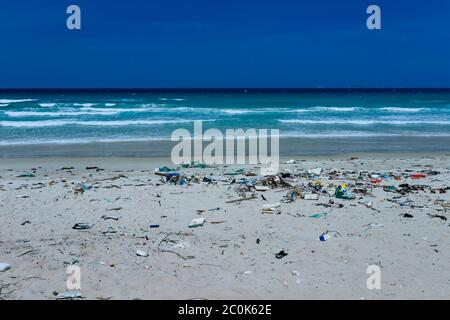 Plastic bottles and other rubbish thrown on the sandy seashore, trash on the sea beach. ecological problem. Environmental pollution. Dirty sandy beach Stock Photo