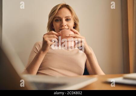 Cheerful young lady enjoying her tea break Stock Photo