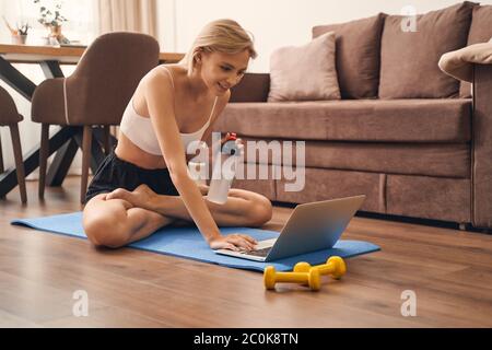 Woman in a lotus pose staring at her laptop screen Stock Photo