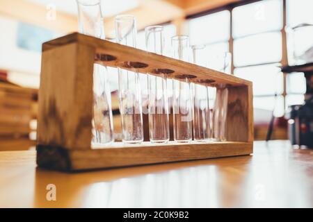 Glass test tubes in wooden stand in chemistry laboratory at high school. Empty testing glass tubes in laboratory. Stock Photo