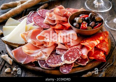 Cures meat platter with cheese and spicy olives served as traditional Spanish tapas on a wooden board. Selection of ham, salami and goat cheese Stock Photo