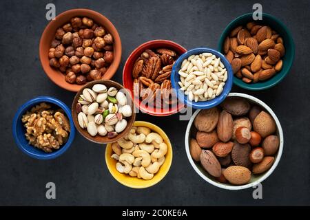 Variety of different types of nuts - almonds, pine nuts, pastachio, cashew, walnuts, pecan and hazelnuts- in bowls. Overhead view Stock Photo