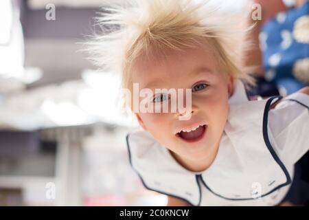 Funny two years old child, boy, hanging upside down, smiling happily, mom holding him Stock Photo