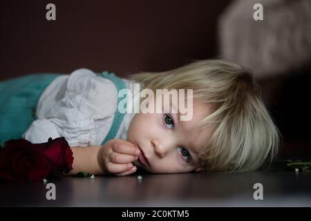 Beautiful toddler boy, holding red roses as present for mother's day Stock Photo