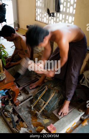 Young craftsman punching gold with a hammer Stock Photo