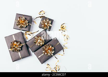 Festive black gift boxes with golden bows and ribbons on white background with copy space, top view. Stock Photo