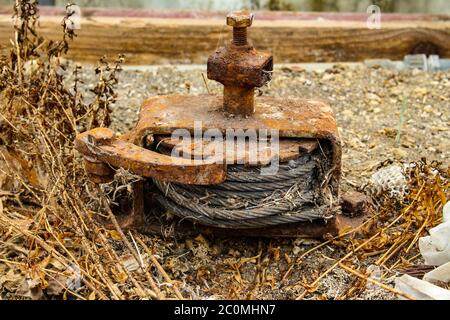 Old rusty winch with ratchet and pawl mechanism and a steel cable rolled up inside Stock Photo