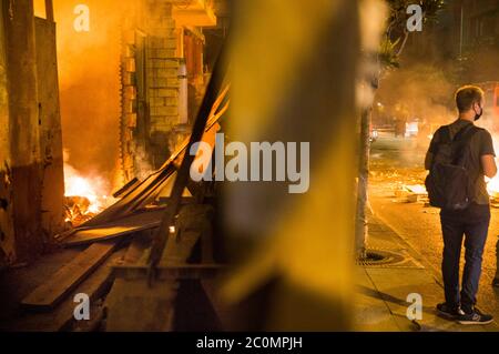 Beirut, Lebanon. 11th June, 2020. A fire, lit by protestors, burns inside a building under construction while a man watches as fire on the street during protesting in Beirut, Lebanon on June 11, 2020. People were protesting as the Lebanese LiraÃs value fell to 5,000 L.L. per $1, with some protestors saying it fell to 7,000 L.L. per $1. Credit: Daniel Carde/ZUMA Wire/Alamy Live News Stock Photo