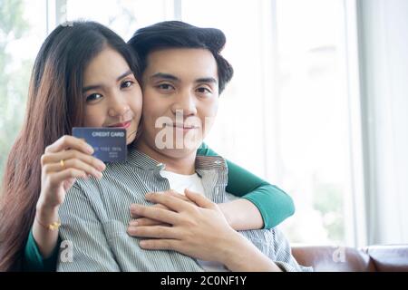 Couples help each other online shopping with credit cards. Stock Photo