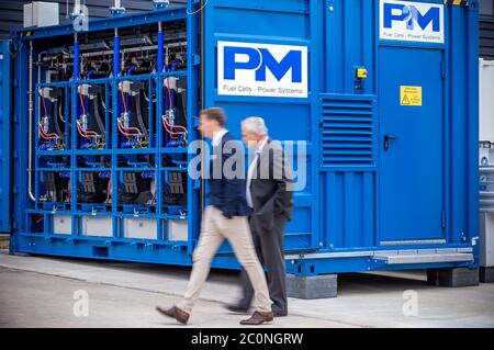 Laage, Germany. 12th June, 2020. Guests of the opening ceremony of the company Apex Energy pass by the fuel cell in what the company says is the largest grid-connected hydrogen power plant in Europe. From autumn 2020 on, Apex will supply green energy for industry and trade, housing companies, public transport or for the intermediate storage of control energy. In this way, up to 300 tons of hydrogen can be produced annually from exclusively renewable energy sources. Credit: Jens Büttner/dpa-Zentralbild/dpa/Alamy Live News Stock Photo