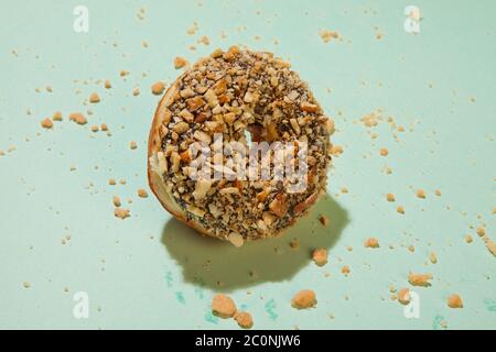 Chocolate doughnut with nuts topping on green background Stock Photo