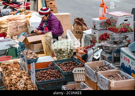 Old lady vendor selling chestnuts, ginger, fish and other goods on a street in Seoul South Korea Stock Photo