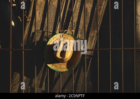 Mexican straw hat with green border on sunlit dark brown wooden fence Stock Photo