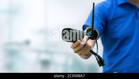 security cameras and cctv services background - man holding ip camera in hand with copy space Stock Photo