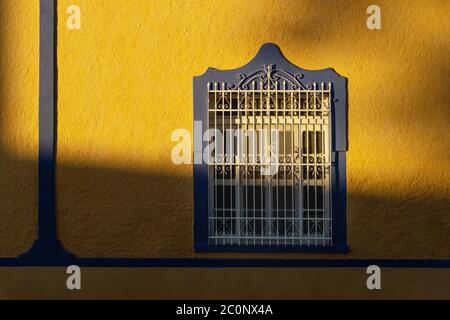 Sunlit facade of colorful colonial window with beautiful shadows in Merida, Yucatan, Mexico Stock Photo