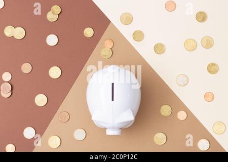 White piggy bank with many euro coins around viewed from above with a Brown colored background made from card stock Stock Photo