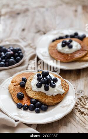 Vertical image of the oatmeal pancakes topped with yogurt and blueberries.  Negative space. Stock Photo