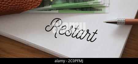 Restart wrd on a page of copybook and 100 Euro bills. Business rebranding concept Stock Photo