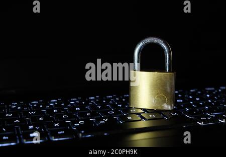 Padlock made of hardened steel on backlit laptop keyboard. Security and cyber crime concept. Stock Photo