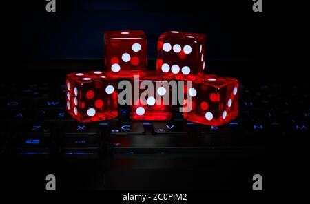 Red dice on backlit laptop keyboard. Gambling and online gaming concept. Stock Photo