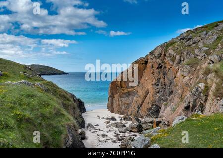 ACHMELVICH BAY AND BEACH SUTHERLAND HIGHLANDS SCOTLAND A COVE WITH BLUE  SKY WHITE SAND AND ORANGE COLOURED ROCKS Stock Photo