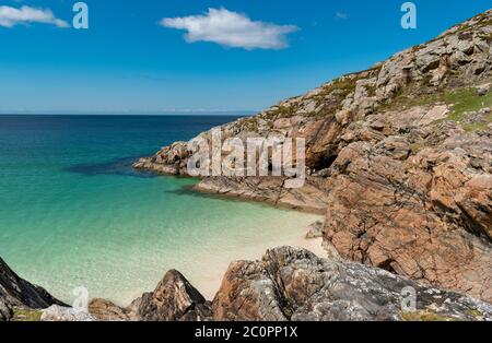 ACHMELVICH BAY AND BEACH SUTHERLAND HIGHLANDS SCOTLAND A SMALL COVE WITH BLUE  SKY COLOURS OF THE SEA AND ORANGE COLOURED ROCKS Stock Photo