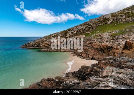 ACHMELVICH BAY AND BEACH SUTHERLAND HIGHLANDS SCOTLAND A SMALL COVE WITH BLUE  SKY THE COLOURS OF THE SEA AND ORANGE COLOURED ROCKS Stock Photo