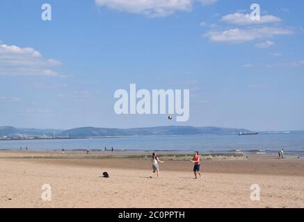 Young couple is playing with ball on sandy beach on a nice day. Stock Photo